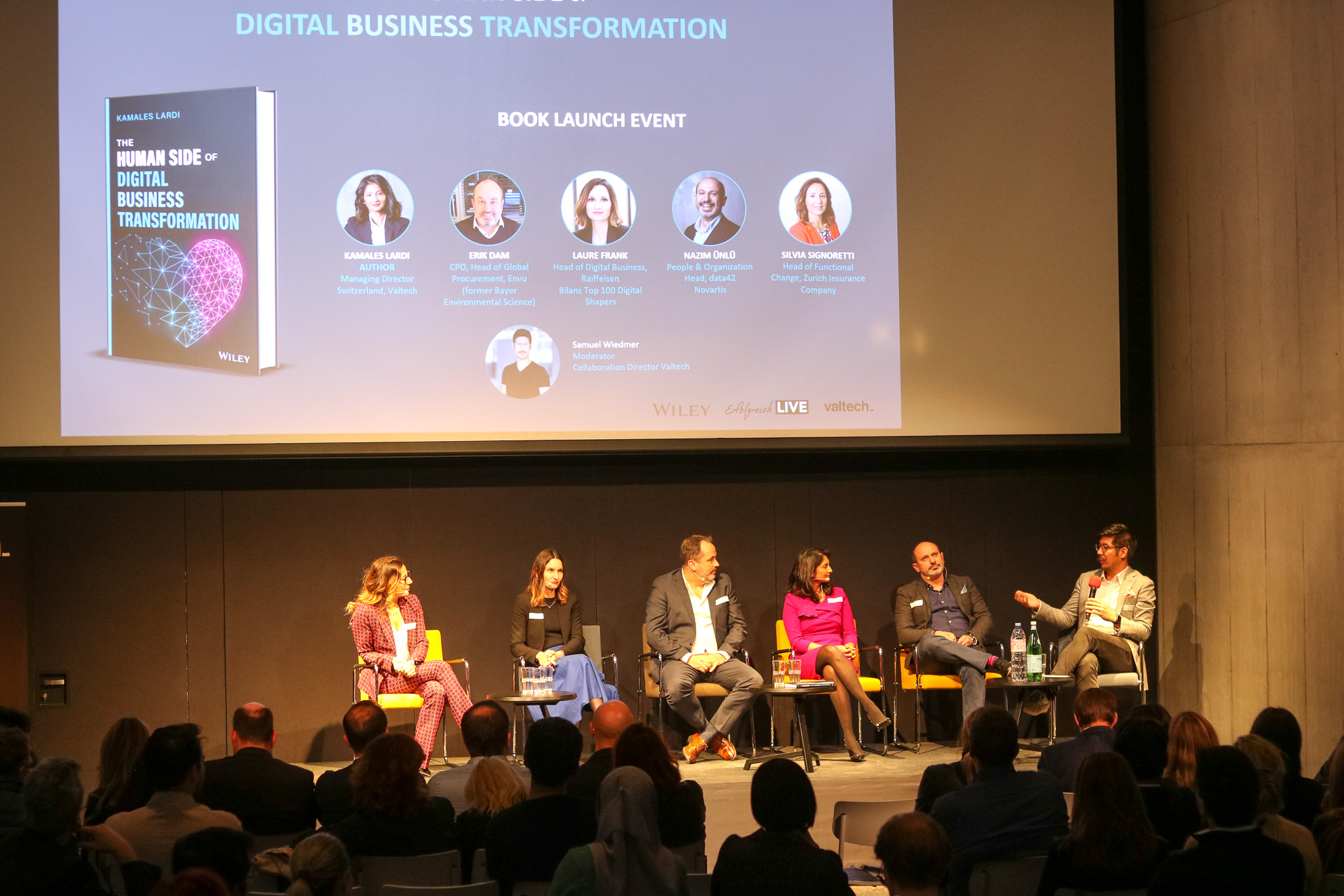 Panel on stage in front of a projected book launch slide
