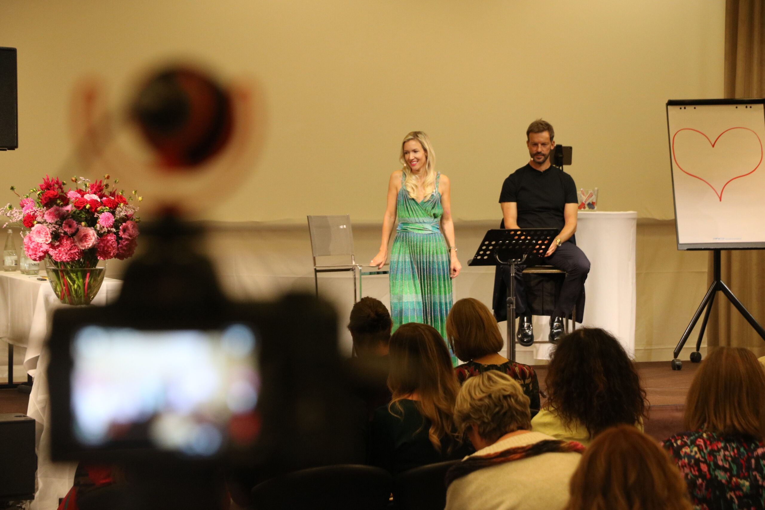 Speakers on stage filmed over a camera in the foreground